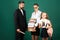 Portrait of father tutor and school kids daughters on green blackboard background. Reading book and writing. Dad