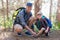 Portrait of father tying shoelace for son in forest