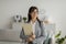 Portrait of female arab psychotherapist with clipboard looking aside and smiling, standing at modern office, free space