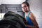 Portrait of female athlete pushing tire in gym