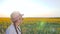 Portrait female in backlight on background blue sky and sunflowers, girl in glasses and hat beside with field of