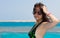 Portrait of female in black-green swimsuit adjusting her hair while standing on the nose of the yacht