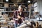 Portrait of female carpenter with goggles working on her product indoors in carpentry workshop. Small business concept.