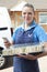 Portrait Of Female Caterer Delivering Tray Of Sandwiches To House Checking Text Message On Mobile Phone