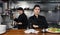 Portrait of female chef with crossed arms along with team of cooks in kitchen of restaurant