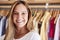 Portrait Of Female Customer Or Owner Standing By Racks Of Clothes In Independent Fashion Store