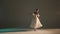 Portrait of female on dark background in low light studio. Pretty ballerina in white tulle demonstrating element of