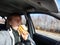 Portrait of female driver in solo journey. Adult mature middle aged woman holding steering wheel and banana. Eating