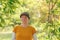 Portrait of female farm worker wearing orange t-shirt and trucker`s hat in walnut tree orchard