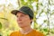 Portrait of female farm worker wearing orange t-shirt and trucker`s hat in walnut tree orchard