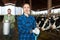 Portrait of female farmer with shovel standing in cowshed