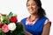 Portrait Of Female Florist Arranging Bouquet Of Lillies And Roses Against White Background