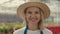 Portrait of the female gardener looking and smiling at the camera wearing straw hat. People and professions concept.