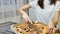 Portrait of female hands cuting a hot pizza with mushrooms, cheese, maize, olives, red onion rings and tomatoes in a