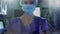 Portrait of female health worker wearing face mask at hospital against time-lapse of people walking