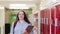 Portrait Of Female High School Student Walking Down Corridor And Smiling At Camera