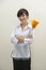Portrait of female housekeeper holding feather duster against gray background