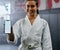 Portrait of a female karate student holding tech with social media, looking active and fit at class. Blank screen on