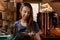 Portrait of a female leather artisan in her workshop with hand-made belt