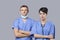Portrait of female and male surgeons standing with arms crossed over gray background