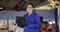 Portrait of female mechanic taking notes on clipboard and smiling at a car service station