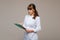 Portrait of a female medical worker in a gray background with a medical report.Girl doctor with a Notepad