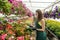 Portrait of female nursery at work in greenhouse, holding clipboard and checks the condition plants