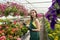 Portrait of female nursery at work in greenhouse, holding clipboard and checks the condition plants