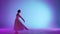 Portrait of female on purple background in pink neon light studio. Gentle ballerina in white tulle showing beautiful