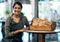 Portrait of a female restaurant waiter, baker or coffee shop retail manager with fresh bread for breakfast. Smiling