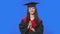 Portrait of female student in cap and gown graduation costume clapping happily. Young brunette woman posing in studio