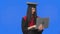 Portrait of female student in cap and gown graduation costume, communicates online using a laptop. Young woman posing in