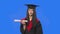Portrait of female student in cap and gown graduation costume, holding diploma and showing thumb down. Young woman