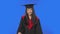 Portrait of female student in cap and gown graduation costume smiling and blowing kiss. Young brunette woman posing in