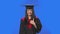 Portrait of female student in graduation costume pointing side hand for something then nods and shows thumb like. Young