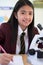 Portrait Of Female Student In Uniform Using Microscope In Science Class