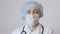 Portrait of female surgeon, medical mask is protection face, close up. Doctor looks at camera.