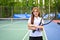 Portrait of female tennis player with racket smiling to camera confidently, showcasing her passion and determination for