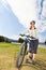 Portrait of female tourist cyclist standing on shore of lake.