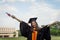 Portrait of a female university graduate wears black academic gown and hat, holds degree certificate with joyful moment after