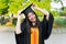 Portrait of a female university graduate wears black academic gown and hat, holds degree certificate with joyful moment after