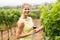 Portrait of female vintner holding wine glass and inspecting grape crop