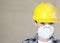 Portrait of female worker wearing dust mask and hardhat over colored background