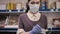 Portrait of female worker wearing a medical mask and gloves takes a Bank card from a customer and processes the online payment at