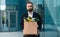 Portrait of fired upset desperate businessman in suit standing outdoors with box of stuff. Male office worker lost job