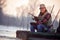 Portrait of fisherman with fishing rod sit on frozen river in th