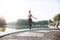 Portrait of fit young woman with jump rope in a park. Fitness female doing skipping workout outdoors on a sunny day.