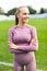 Portrait of fit young woman in sportswear standing on racetrack with her hands folded and looking away in athletics stadium on a