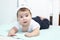 Portrait of five month cheerful infant lying on belly with dressed white headband