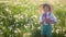 portrait of a five year old boy in a hat stands on a field of dandelions and shoots soap bubbles from a toy gun at